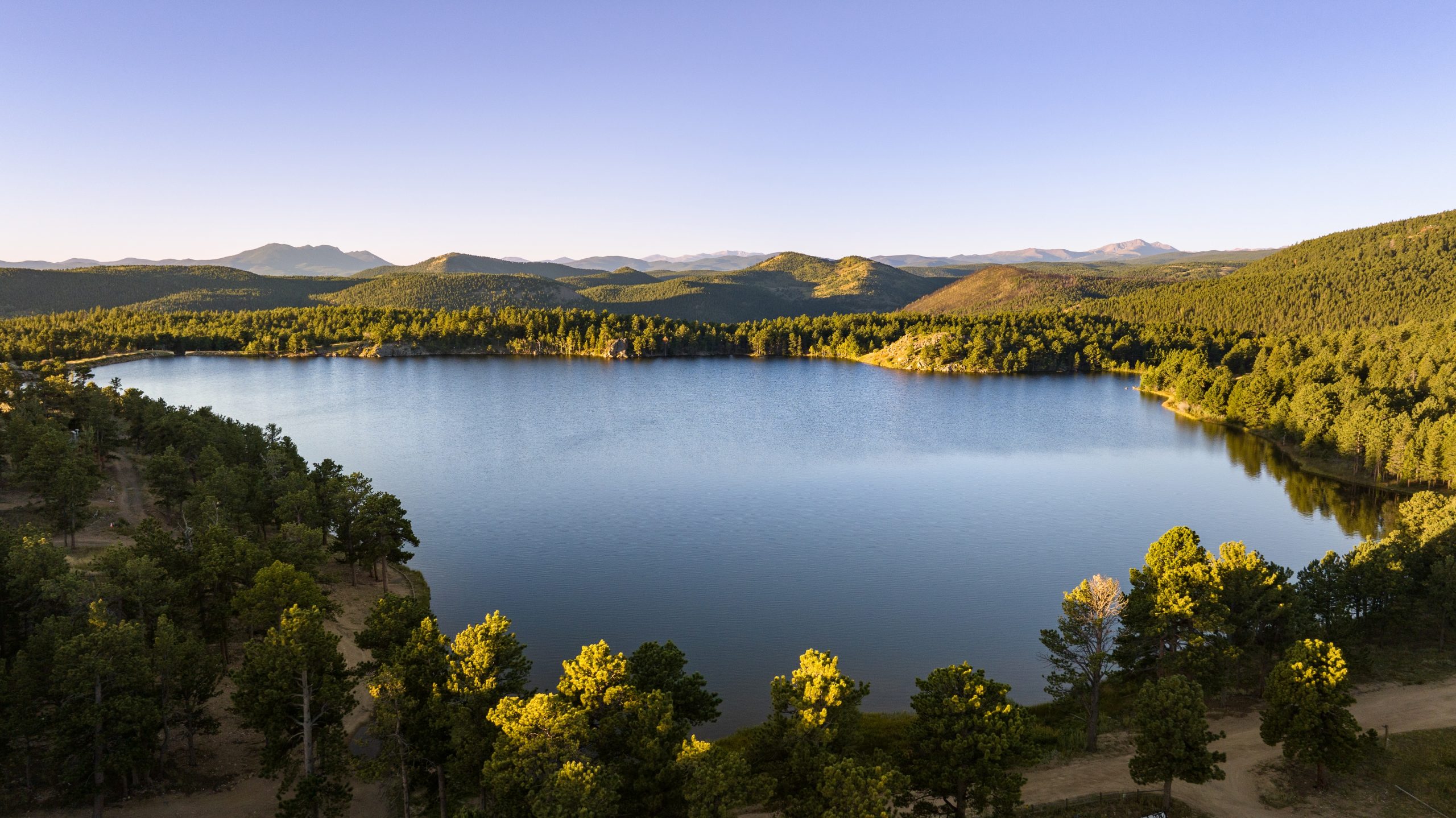 A breathtaking aerial view of Gold Lake, a 99-acre historic luxury real estate property in Boulder County, surrounded by forested hills and expansive mountain views.